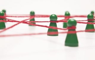 Grüne Spielfiguren verbunden durch einen roten Faden